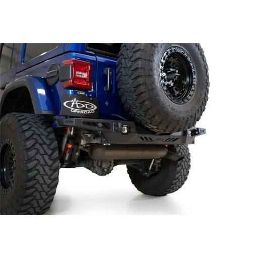 Blue jeep with large tire on addictive desert designs wrangler jl stealth fighter rear bumper