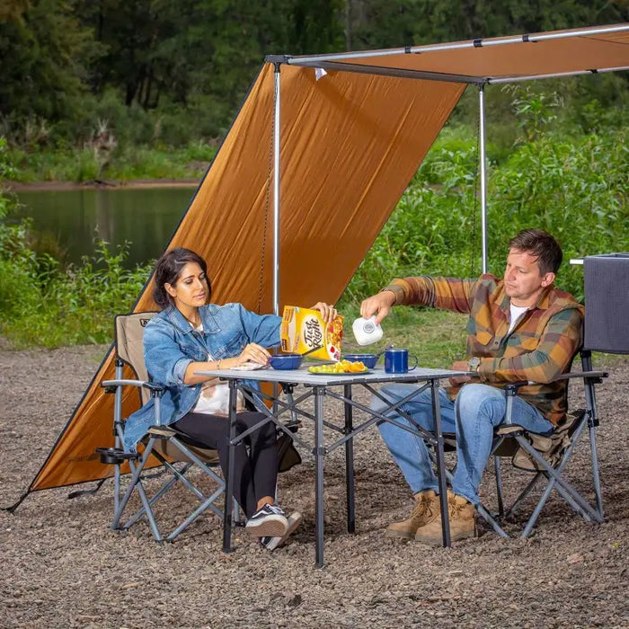 Couple sitting at ARB Aluminum Camp Table in the woods.