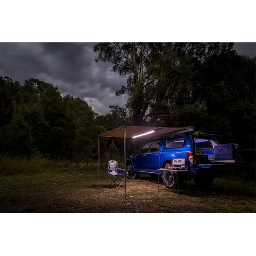 ARB awning light LED strip on blue van parked in woods at night.