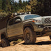 Gray Toyota Tacoma truck driving down a dirt road