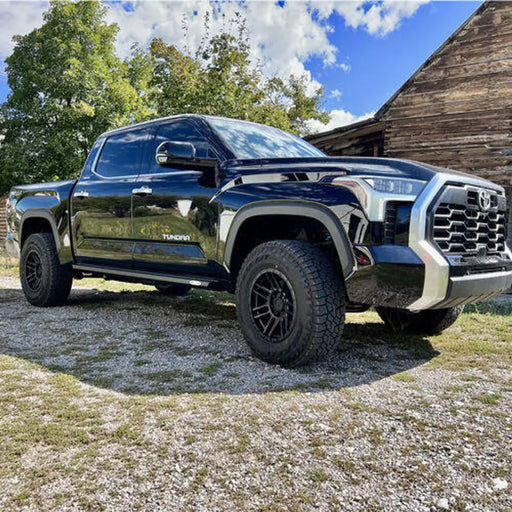Black Toyota Tundra parked in front of a barn