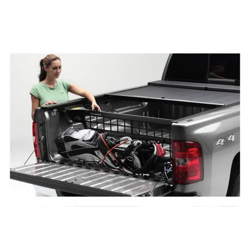 Woman loading tool in Roll-N-Lock Cargo Manager for 20-22 Jeep Gladiator, truck bed.