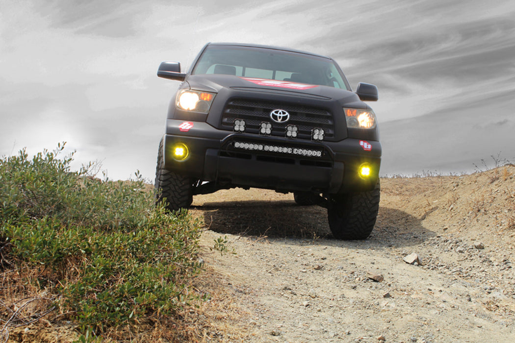 Black Toyota Tacoma driving down a dirt road.