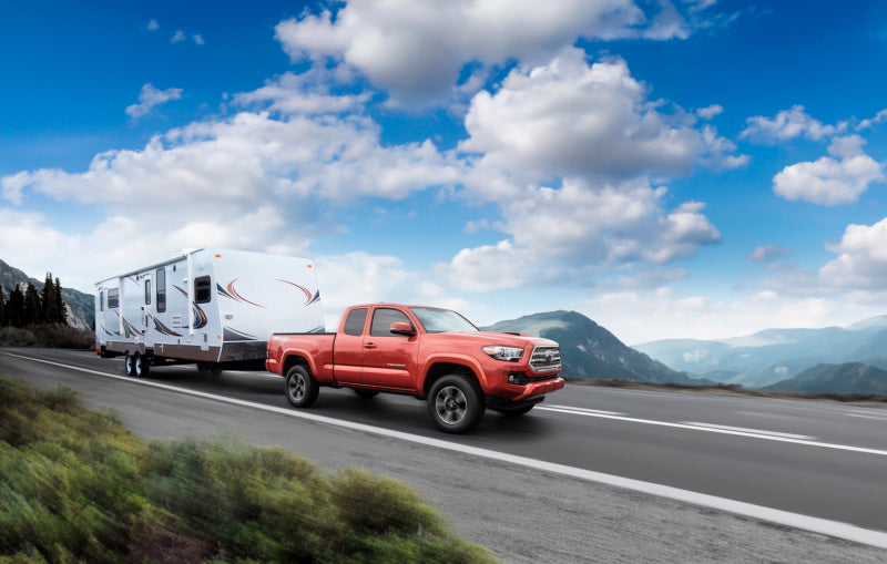 Red truck towing a trailer on road with air lift loadlifter 5000 air spring kit for toyota tacoma