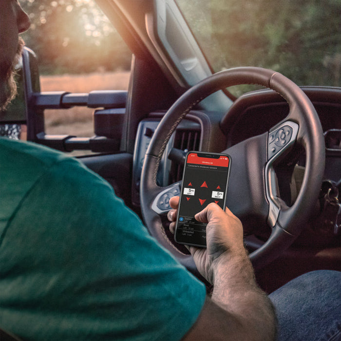 Man using smartphone while driving truck, controlling air springs with air lift wireless air control system w/ wireless phone app