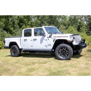 AMP Research Jeep Gladiator PowerStep XL in Black parked in a field with trees.