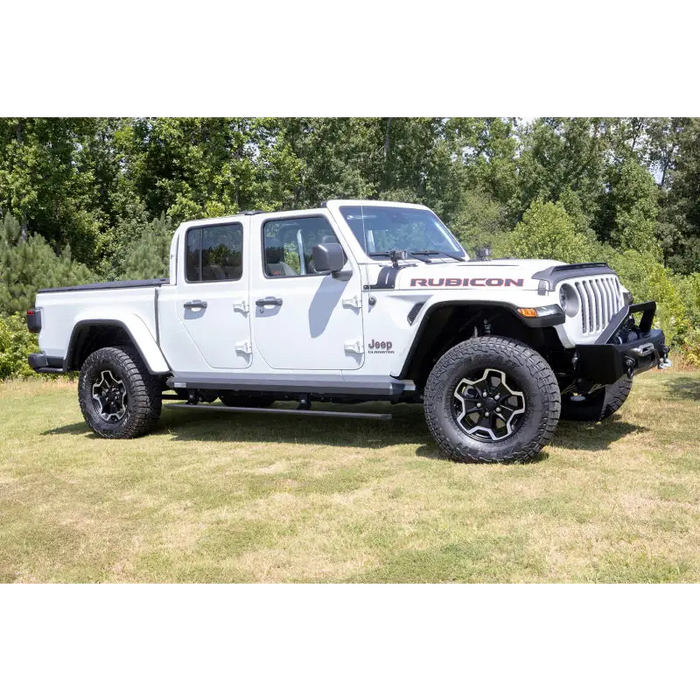 AMP Research Jeep Gladiator PowerStep XL in Black parked in a field with trees.