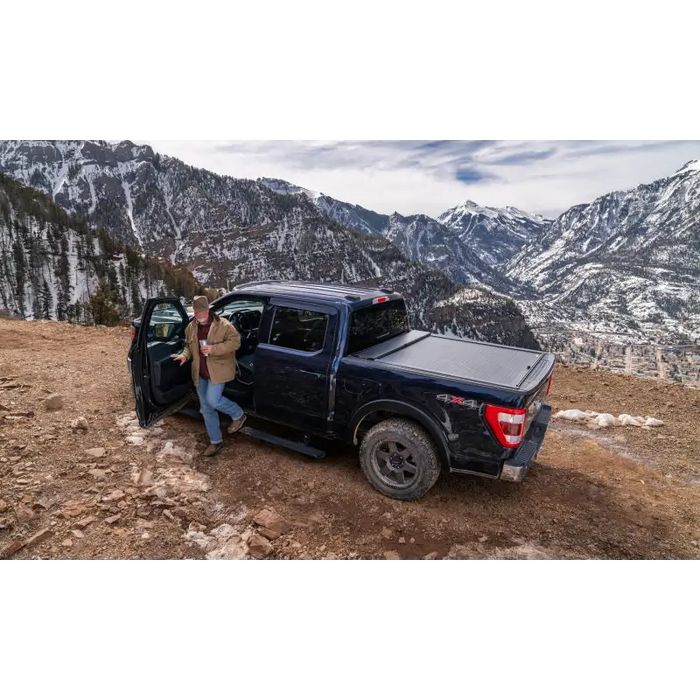 Man standing next to a truck on a mountain with AMP Research Powerstep Plug N Play - Black