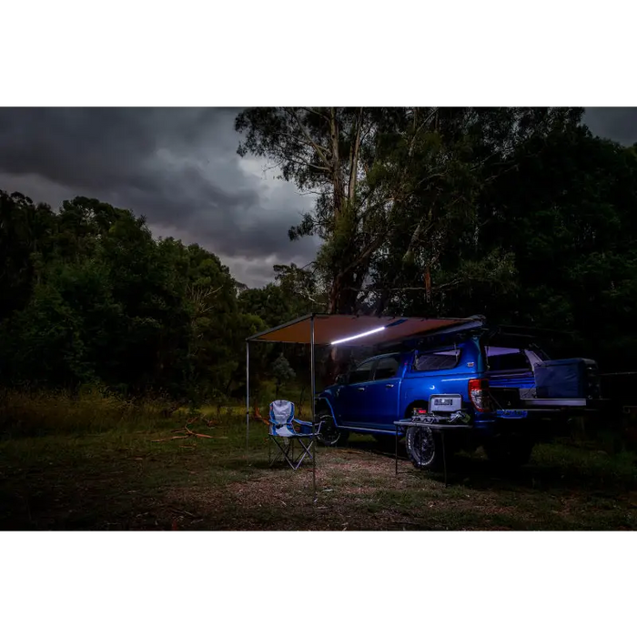 Blue van parked under dark sky in woods next to ARB Awning w/Light 6.5ft x 8.2ft