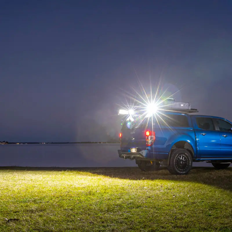 Blue truck parked by lake next to ARB BaseRack Auxiliary Light - 2.8in 20W