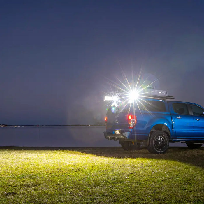 Blue truck parked by lake next to ARB BaseRack Auxiliary Light - 2.8in 20W