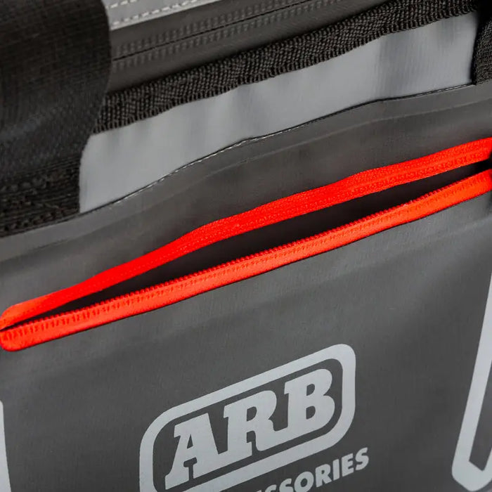 Small black and red ARB cooler bag with zipper holding 22 cans