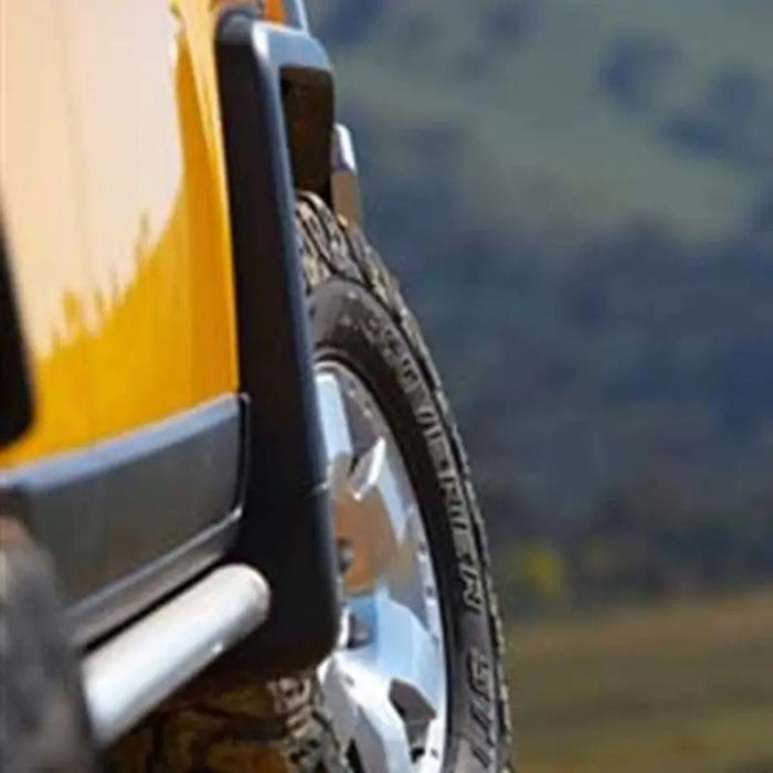 Yellow truck with black tire and rim next to ARB Deluxe Rock Rails for FJ Cruiser