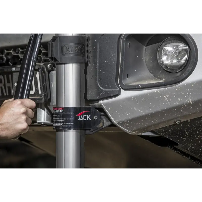 Man using ARB Jack to fix car’s front bumper with hydraulic technology.