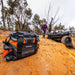 Man carrying a large black and orange bag on a dirt road for ARB Premium Recovery Kit S2.