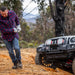 Man using ARB Premium Recovery Kit S2 snatch strap to pull toy car on trail.