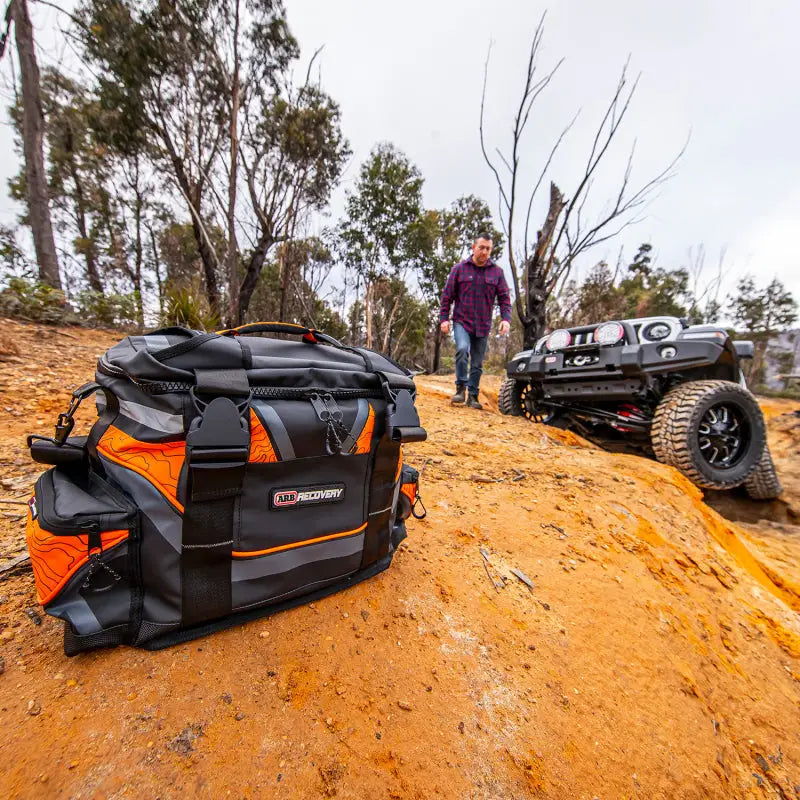 Man standing next to black and orange bag in ARB Premium Recovery Kit S2.