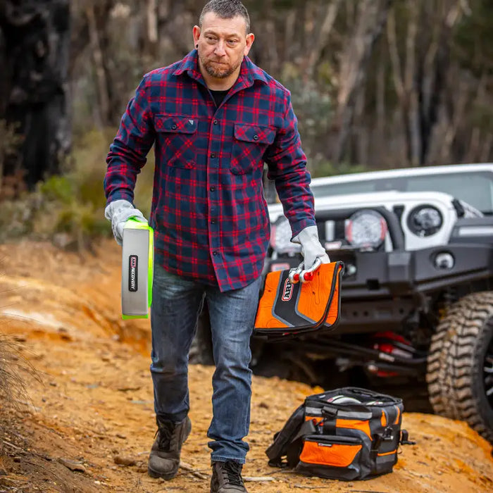 Man in plaid shirt and gloves using chainsaw to cut tree - ARB Premium Recovery Kit S2.