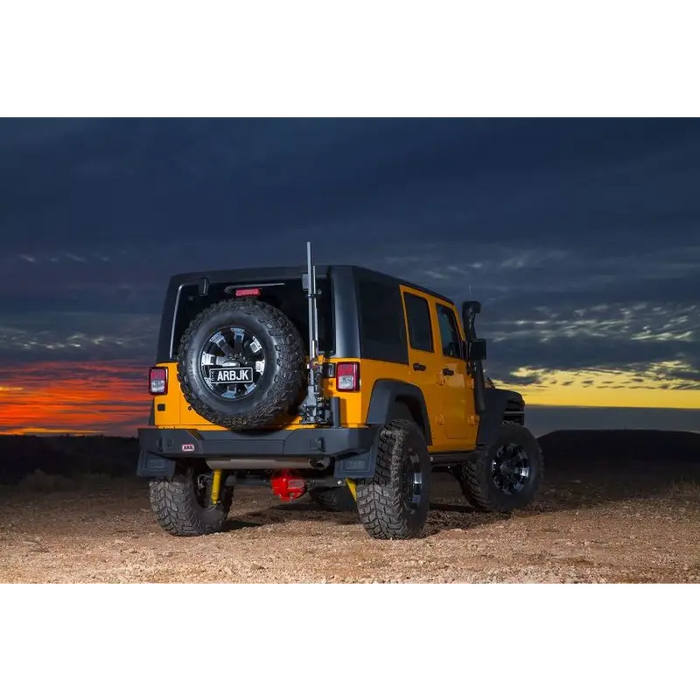 Rear view of yellow Jeep Wrangler with black tire cover