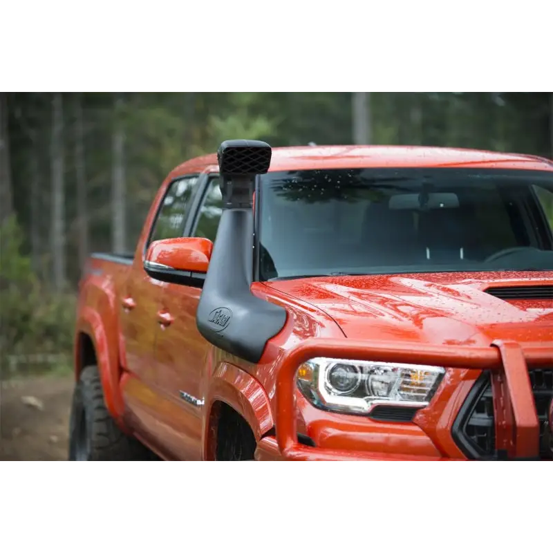 Red truck driving down dirt road with ARB Safari 4x4 Snorkel displayed