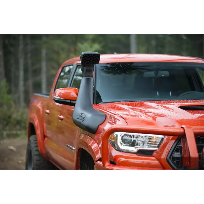 Red truck driving down dirt road with ARB Safari 4x4 Snorkel displayed