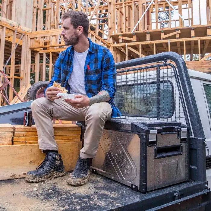 Man sitting on back of truck with dog, ARB Elements Fridge Freezer 63 Quart USA B Plug.