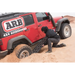 Man using Tred Pro recovery board to fill tire with sand in red jeep