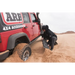 Man using ARB Tred Pro Red recovery board to dig in sand from a jeep