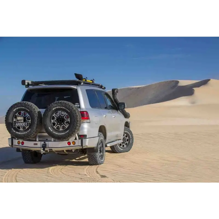 Arb spare tire carrier on silver jeep with black tire cover.