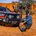 Man kneeling next to red pick truck - ARB Weekender Recovery Kit - 17600lb Recovery Strap/4.75T Shackles