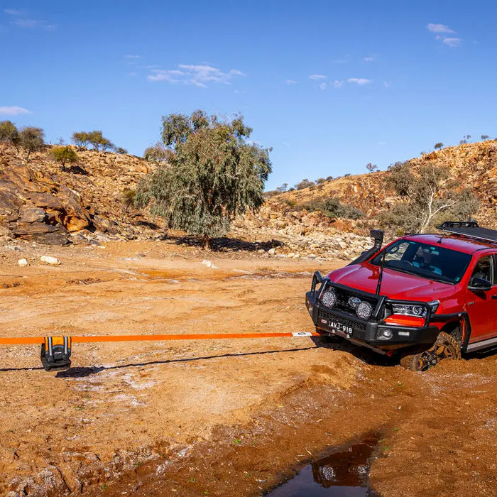 Red car parked on dirt road in front of ARB Weekender Recovery Kit.