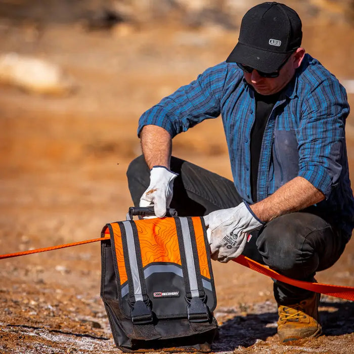 Man kneeling on rock with tool bag - ARB Weekender Recovery Kit - 17600lb Recovery Strap/4.75T Shackles