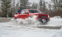 Red truck splashing through puddle with avs original ventvisor window deflectors in smoke