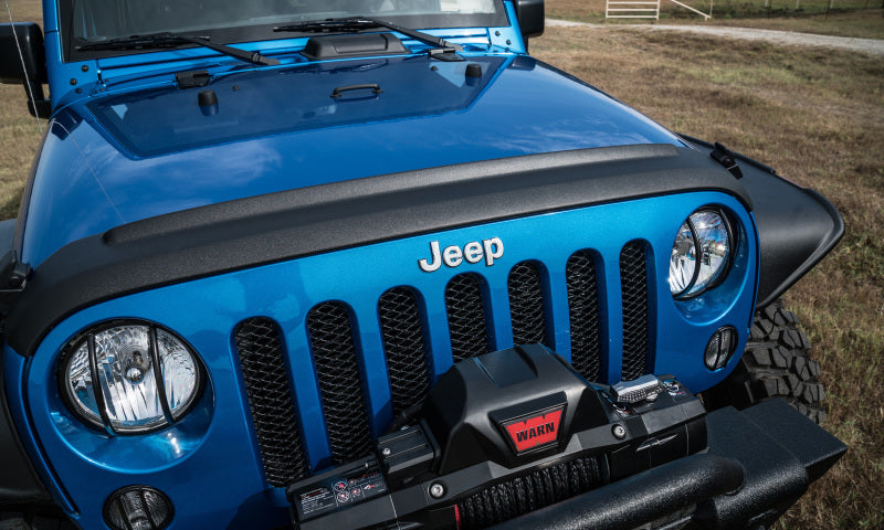 Front view of avs 07-18 jeep wrangler (jk) aeroskin ii textured low profile hood shield in black with jeep logo on hood