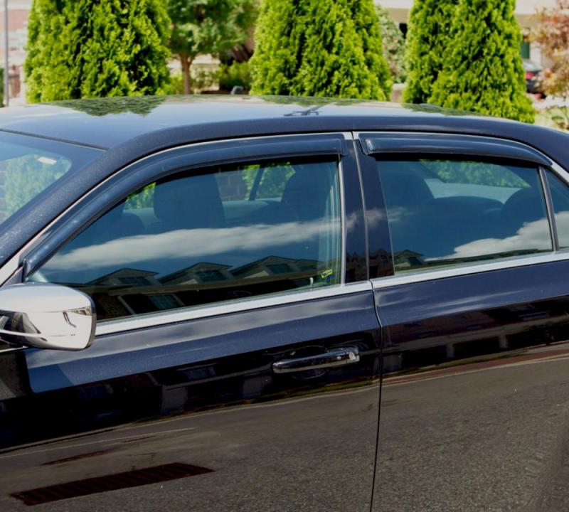 Black car parked in lot with avs original ventvisor window deflectors, allowing fresh air to flow