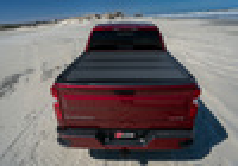 Red car driving on desert road with bak 04-14 chevy silverado 1500 5ft 8in bed bakflip mx4 matte finish