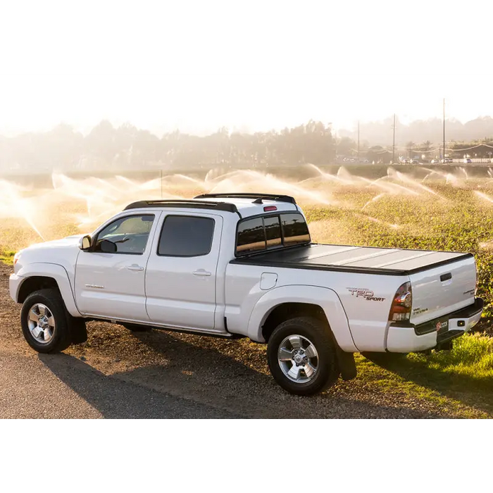 White truck parked on dirt road, BAK 05-15 Toyota Tacoma 5ft Bed BAKFlip G2.