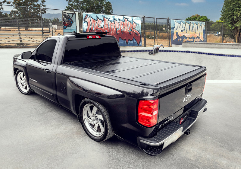 Black chevy silverado truck bed cover by bakflip g2 parked in lot