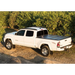 White Toyota Tacoma truck parked in front of bush - BAKFlip G2 truck bed cover.