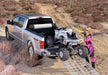 A woman standing next to a truck bed installation - bak 17-23 ford super duty 8ft bed revolver x2