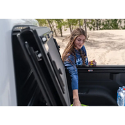 Woman in truck with water bottle next to BAK 2020 Jeep Gladiator BedFlip MX4.