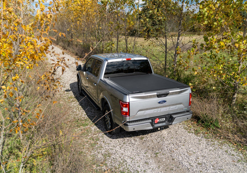 Chevy silverado/gmc sierra truck with revolver x4s bed cover parked on dirt road in woods