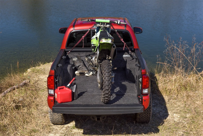 Red car with bike in back shown in bedrug bedliner for toyota tacoma
