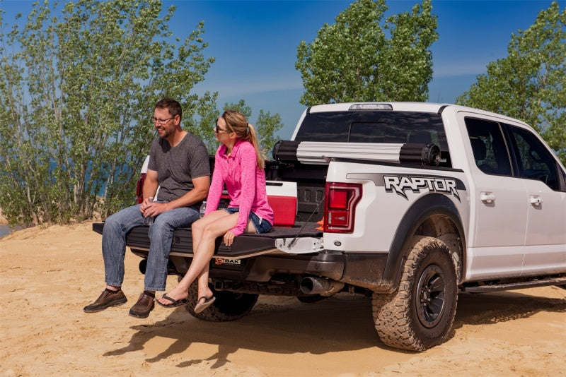 Couple sitting on white truck bed mat with hook & loop design, bedrug 20-23 gmfs hd 6ft9in xlt