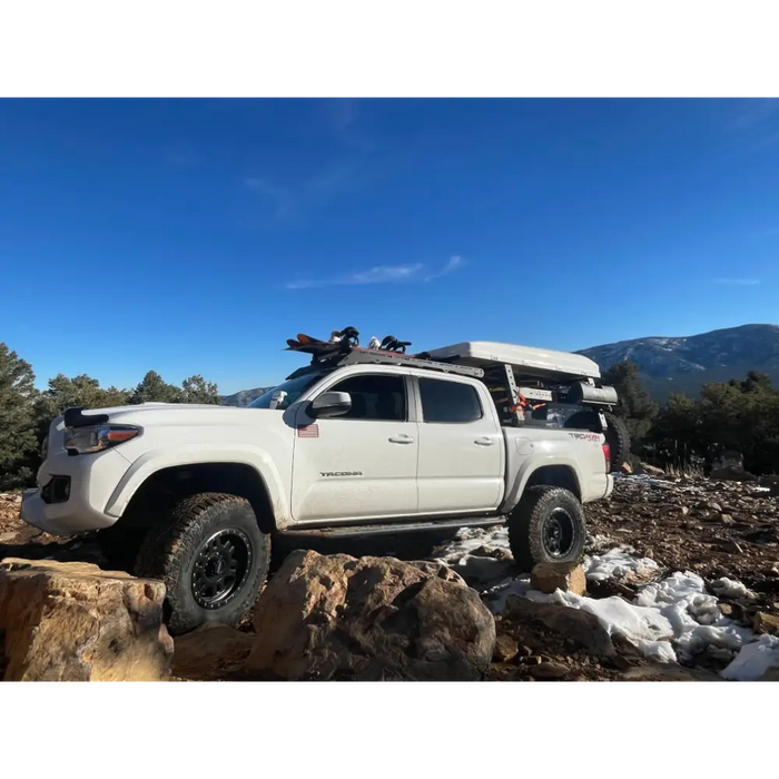 White truck parked on rocky hill near Body Armor 4x4 Toyota Tacoma Double Cab sliders.