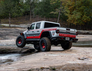 White truck with red accents driving on rocks showcasing bushwacker 2020 jeep gladiator launch edition flat style fender flares