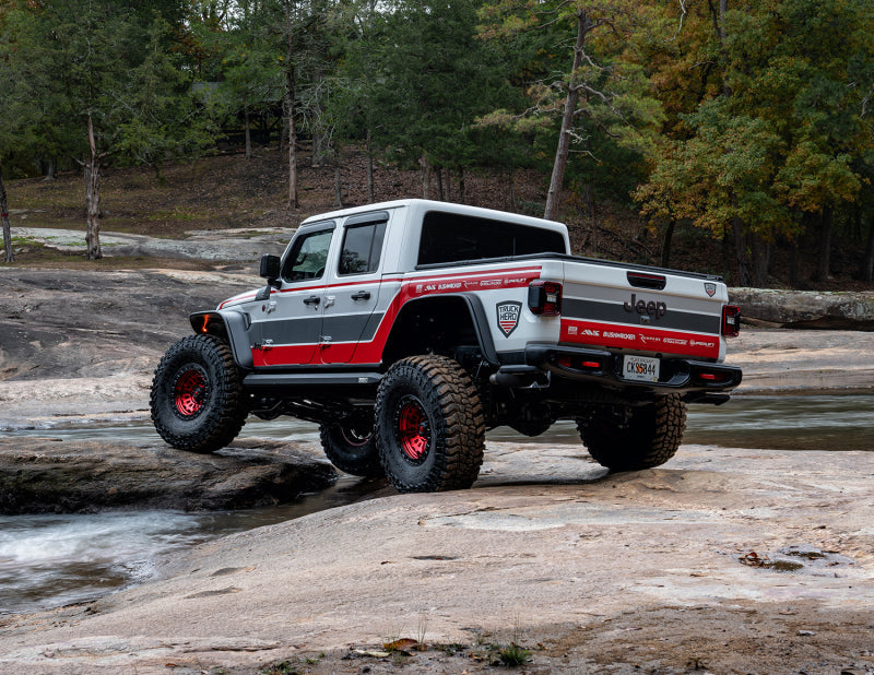 White truck with red accents driving on rocks showcasing bushwacker 2020 jeep gladiator launch edition flat style fender flares