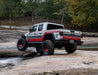 White truck with red accents driving on rocks showcasing bushwacker 2020 jeep gladiator launch edition flat style fender flares