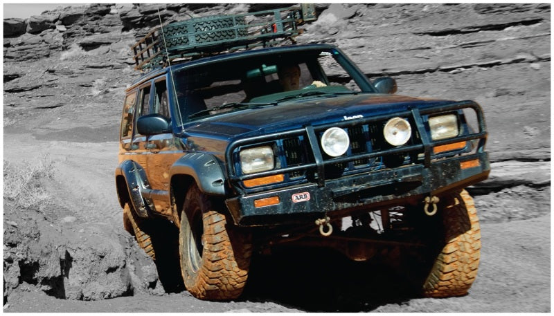 Blue jeep driving rocky terrain with bushwacker fender flares