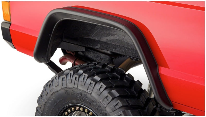 Red truck with big tire showcasing bushwacker 84-01 jeep cherokee flat style fender flares in black